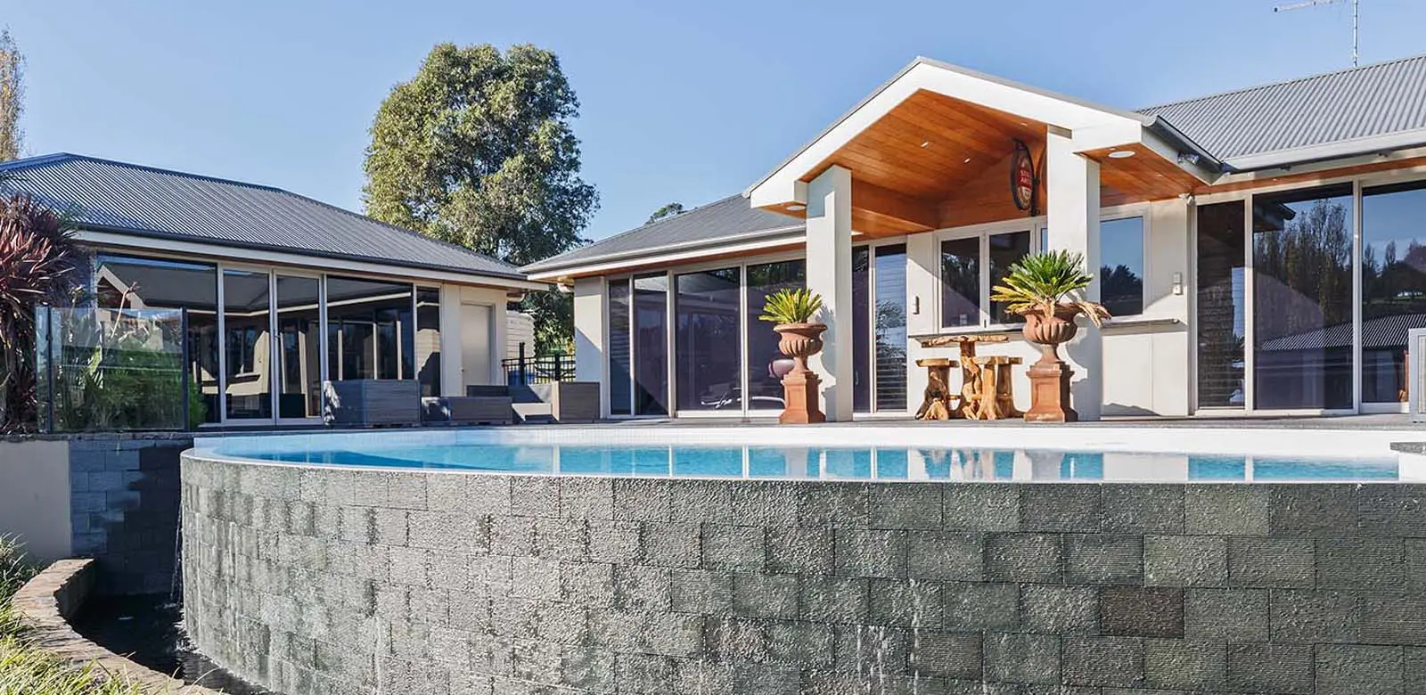 A modern house with a negative edge pool and patio area